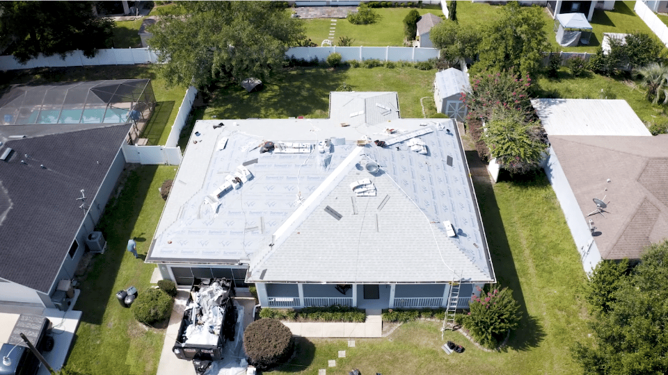 An areial view of a home getting a new gray, asphalt shingle roof installed.