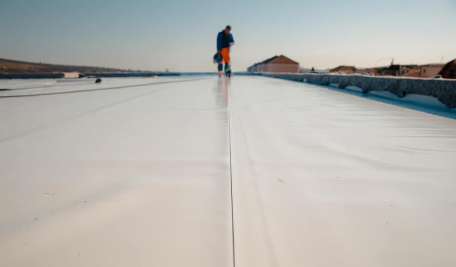An image of a roofer installing a TPO roof on a commercial building. An example of commercial re-roofing.