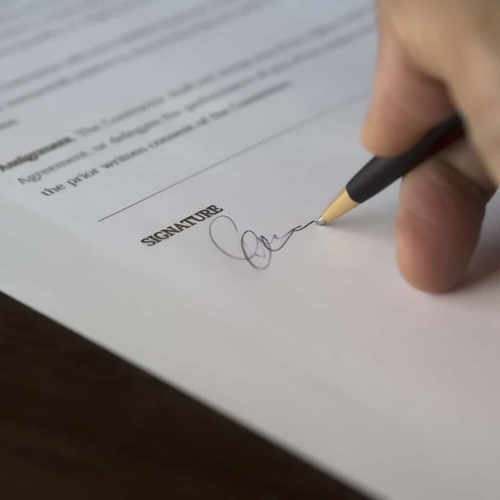 A reputable roofer will file proper permitting paperwork. This is a picture of a person signing a document.